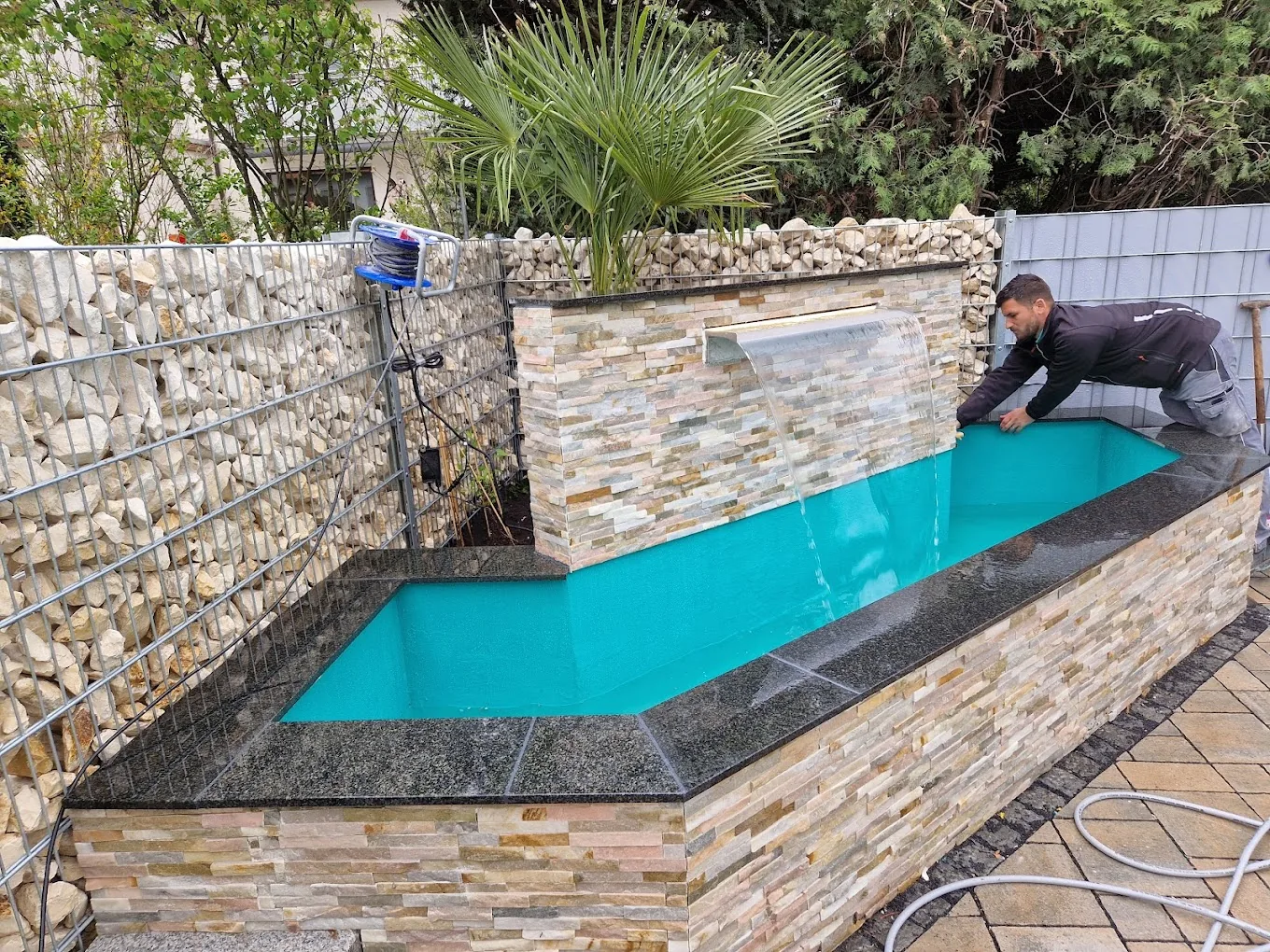 Pool mit Natursteinverkleidung, Granit-Umrandung und Wasserspiel
